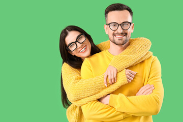 Sticker - Young couple in eyeglasses hugging on green background