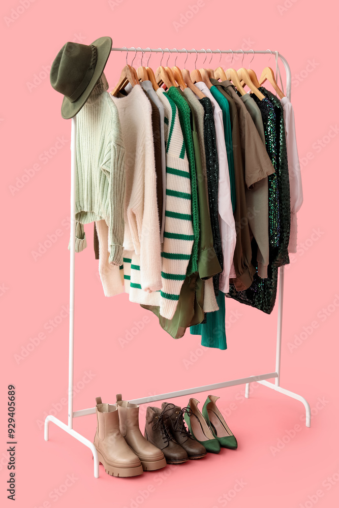 Rack with stylish clothes on pink background
