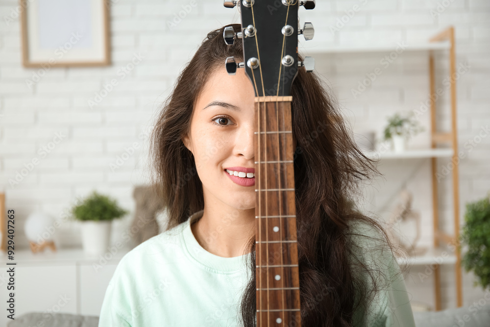 Pretty young woman with guitar at home