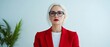 © Alpha - A senior American woman in a stylish red suit, negotiating with poise in a sophisticated, minimalist office environment