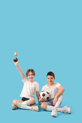 Canvas Print - Happy brothers with soccer ball and gold cup on blue background