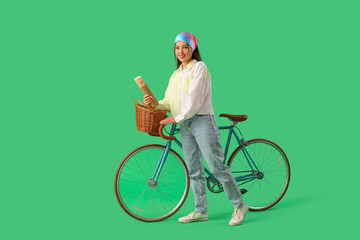 Wall Mural - Young Asian woman with doner kebab and bicycle on green background