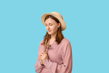 Wall Mural - Religious young woman praying with wooden cross on blue background