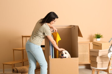 Young happy woman and cute Labrador dog with boxes on moving day at home