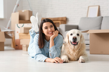 Poster - Young happy woman and cute Labrador dog with boxes on moving day lying at home