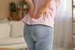 © Pixel-Shot - Young woman suffering from back pain at home, closeup