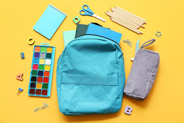 Wall Mural - Modern school backpack with different stationery supplies on yellow background