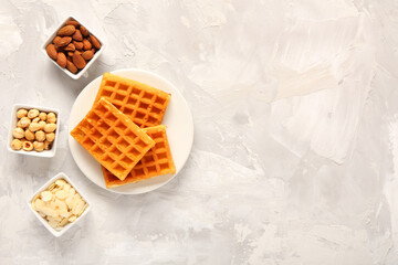 Canvas Print - Plate with tasty Belgian waffles and bowls of different nuts on grey background