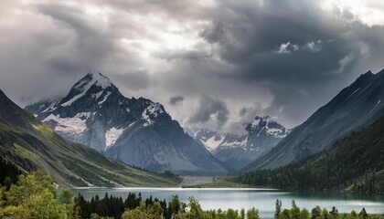 Canvas Print - a mountain range with a lake in the foreground and a cloud studded gray sky in the background