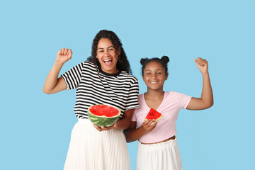 Sticker - Beautiful young African-American woman and her cute daughter with cut fresh watermelon on blue background