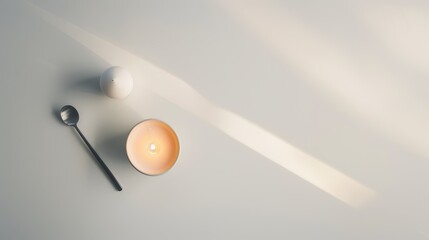 Canvas Print - Simplistic arrangement of a scented candle casting shadows on a white table with a spoon, evoking a serene and comfortable ambiance