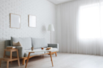 Wall Mural - Blurred view of living room with grey sofa, table and frames