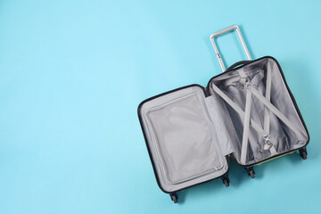 Wall Mural - Open empty suitcase on light blue background, top view. Space for text