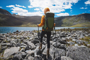 Wall Mural - woman hiking on high altitude mountains, walking to a beautiful lake