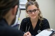 © Box Milk - medical student performing a physical exam on a patient in a clinic. They are using a stethoscope and taking notes