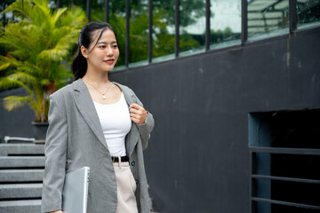 Asian businesswoman in a stylish suit is walking down the stairs in the city