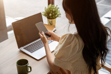 Asian woman working on her smart phone in a modern coffee shop