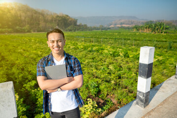 Poster - A young man is standing in a field with a tablet in his hand