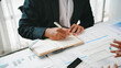 © amnaj - Businessman taking notes in his diary during a financial meeting using graphs and spreadsheets