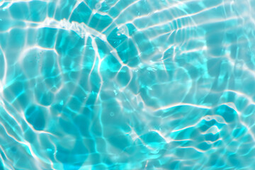 Blue water with ripples on the surface. Defocus blurred transparent blue colored clear calm water surface texture with splashes and bubbles. Water waves with shining pattern texture background.