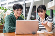 © bongkarn - Two young Asian college students are discussing work and doing on a co-project together.