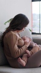 caring caucasian mother breastfeed toddler son on living room sofa at home. motherhood, childcare an