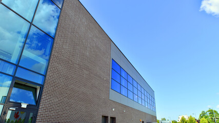 Wall Mural - Fragment of a modern building made of steel and glass. Abstract modern commercial architecture fragment. Walls made of shiny glass and steel under blue sky.