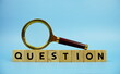 © may1985 - Question with wooden blocks alphabet letters and Magnifying glass on blue background