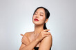 © bongkarn - A gorgeous Asian beauty model with glowing tanned skin poses, touching her skin with her eyes closed