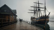 © Shinso_Hajime - Vintage wooden ship docked at an old pier, with ropes and barrels around, set against a foggy backdrop.
