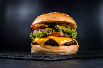 delicious cheeseburger with lettuce, tomato, onion, bacon, and melted cheese, on a sesame seed bun, 