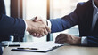 © halo - A photograph of two businessmen shaking hands over an office desk, with documents and stationery in the background.