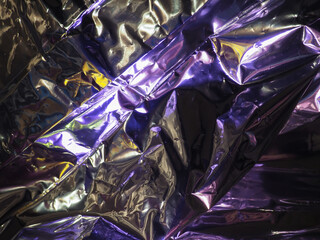 Wall Mural - purple light reflects on silver plastic sheet for abstract dark background.
