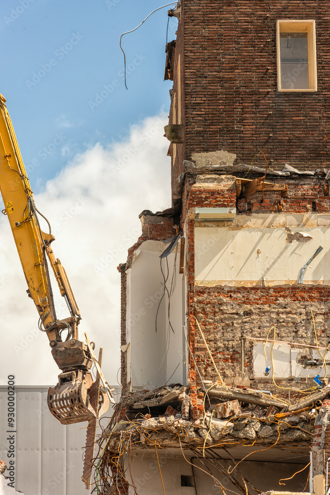 steel sorting grab of a demolition machine is demolishing a building
