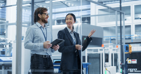 Fototapete - Portrait of an Experienced Male and Female Engineers Walking in Agency Room, Using Computer Tablet Device and Discussing Production at a Modern Automated Electronics Manufacture with Robotic Arms