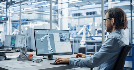 Fototapete - Portrait of a Young Factory Manager Working on Desktop Computer in Industrial Manufacture with Autonomous Assembly Robots. Production Line Making Heavy Machinery Parts in the Background