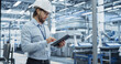 © Gorodenkoff - Electronics Factory Manager Working on Tablet at an Industrial Manufacture with Robotic Arms. Specialist in a Hard Hat Monitoring Big Data on a Computer, Checking and Planning Production Numbers