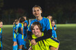 © PoppyPix - little goalkeeper girl carrying her teammate girl with her back, soccer practice, medium shot. High quality photo