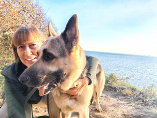 a woman is happily holding a german shepherd dog while at the beach