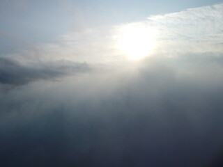 Wall Mural - aerial view. blue sky sun and fog over calm sea. the drone flies over foggy and fluffy clouds. abstr