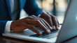 © Chatchanan - Close-up of a businessman's hands on a laptop keyboard, incident management icon visible on the screen, focused on solving issues