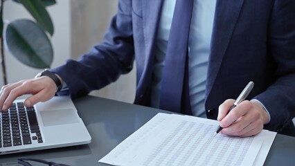 Businessman analyzing financial data on laptop and calculator. Close-up of a professional auditor working on financial reports. Business concept