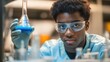 © sknab - Young African American Male Scientist Focused on Experiment with Blue Substance in Laboratory