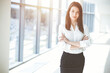 © volha_r - Beautiful female specialist with arms crossed standing in sunny office and smiling charmingly. Business people concept