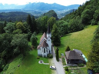 Wall Mural - Aerial view of Kuratienkirche Meschach surrounded by lush greenery. Gotzis, Austria