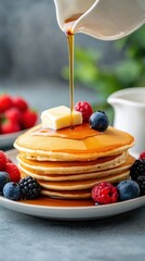 A plate of fluffy pancakes topped with a generous pour of maple syrup and a pat of melting butter, with a side of fresh berries for a breakfast-inspired dessert