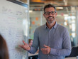 © Seoyoung Jang - A business professional in a modern office space, standing at a whiteboard while explaining a project to colleagues during a team meeting