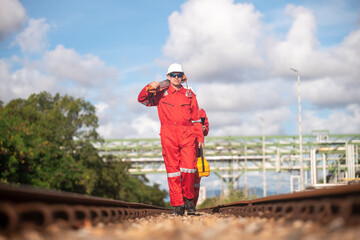 Surveyor engineers team wearing safety uniform and blueprint checking inspection by theodolite telescope to measurement level position railway construction site is industry transportation concept.