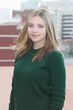 © atikinka2 - young beautiful girl with long hair and blue eyes in a green olive sweater on a cityscape  background.
