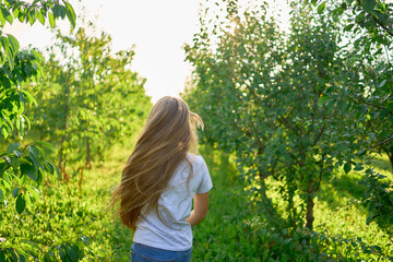 a portrait of a teenage girl with long blond hair in a sunlit garden